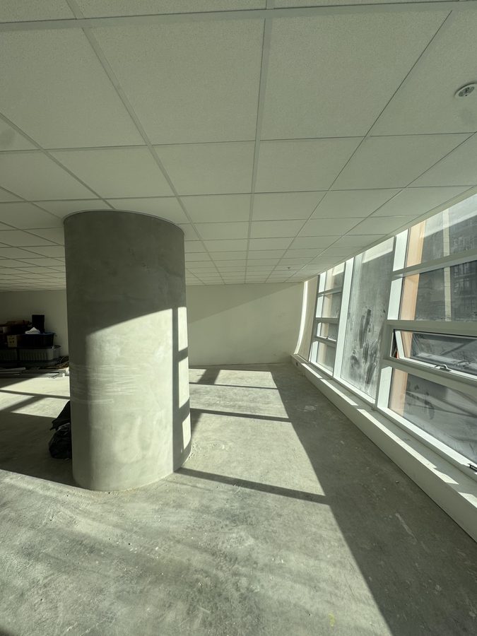 A finished acoustic tile ceiling over an office floor with a round concrete column