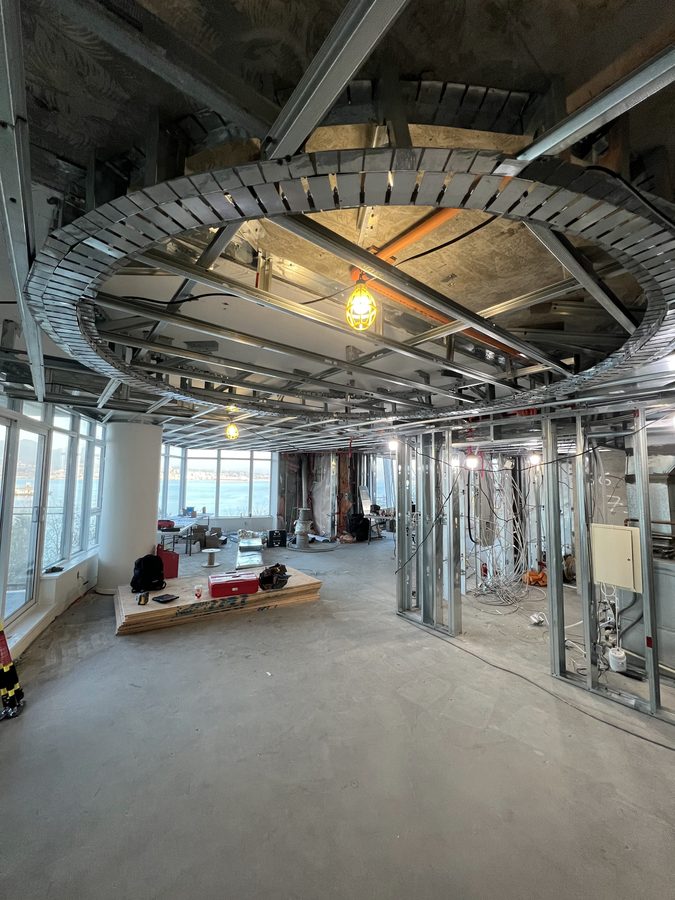 Steel framing for a circular ceiling feature in a high-rise suite with windows behind