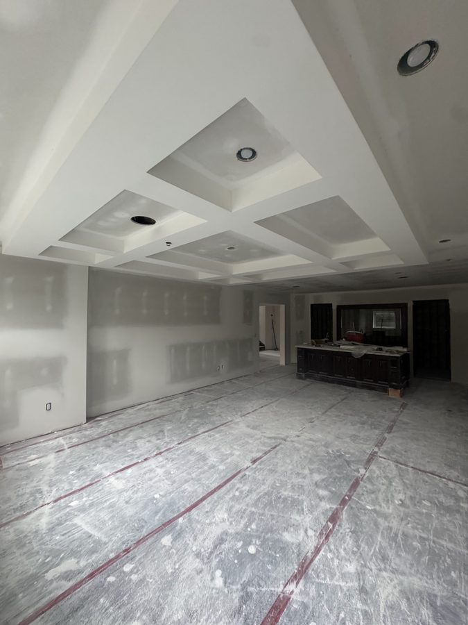 A coffered drywall ceiling with taped joints above an open living area