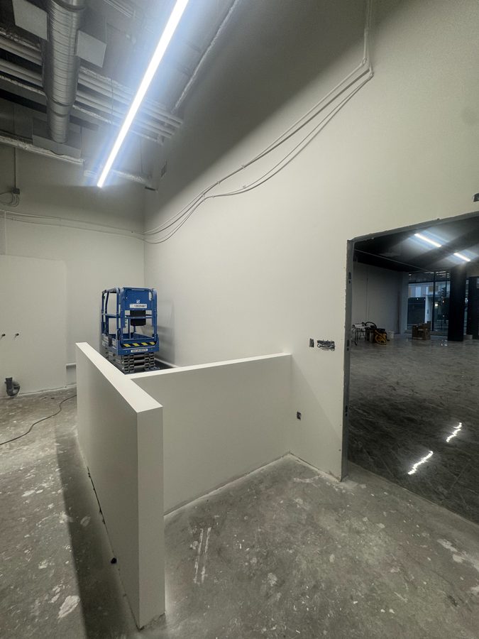 A finished drywall half wall and clean corners in a commercial space with a linear light