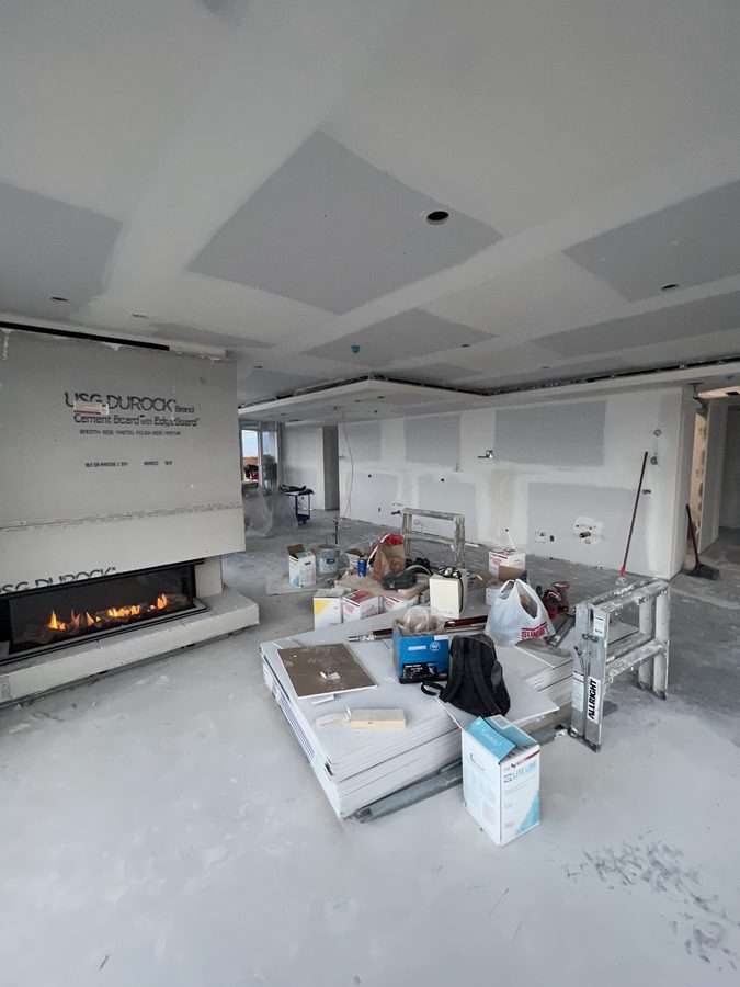 A fireplace surround boarded in cement board under a coffered drywall ceiling