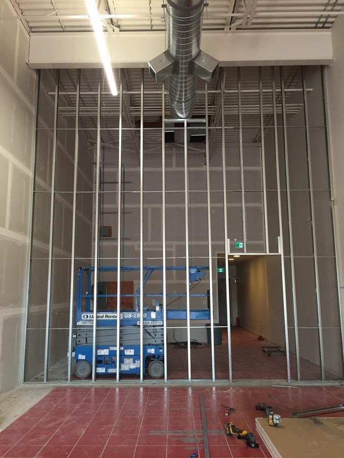 Full-height steel stud wall framing with a scissor lift in front of it