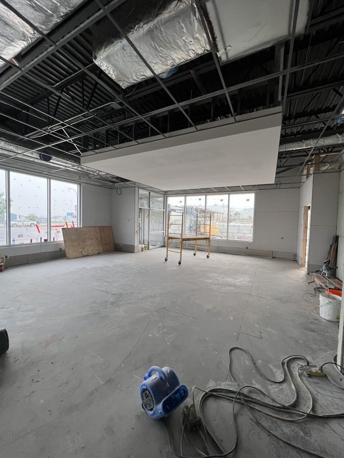 A T-bar ceiling grid and a boarded drywall bulkhead over an open office floor