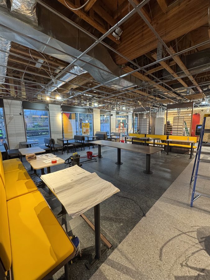 A ceiling grid being installed over a restaurant dining room with yellow bench seating