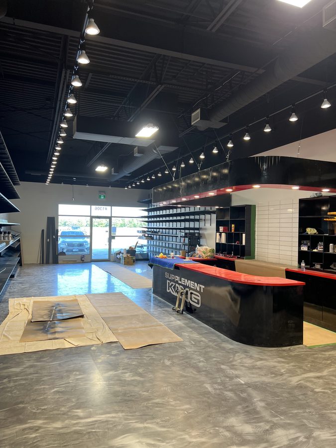 A finished retail store with drywall bulkheads, an open black ceiling and a service counter