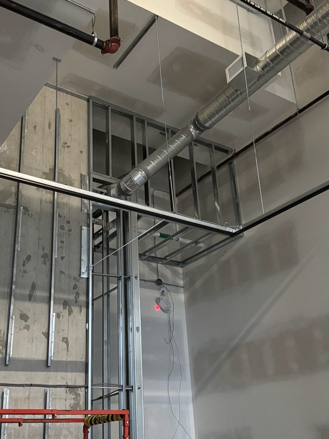 Steel studs and track framing a tall shaft wall beside exposed ductwork