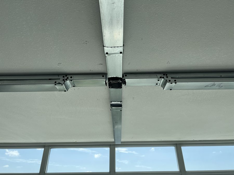 Looking up at crossing steel soffit framing above a row of windows